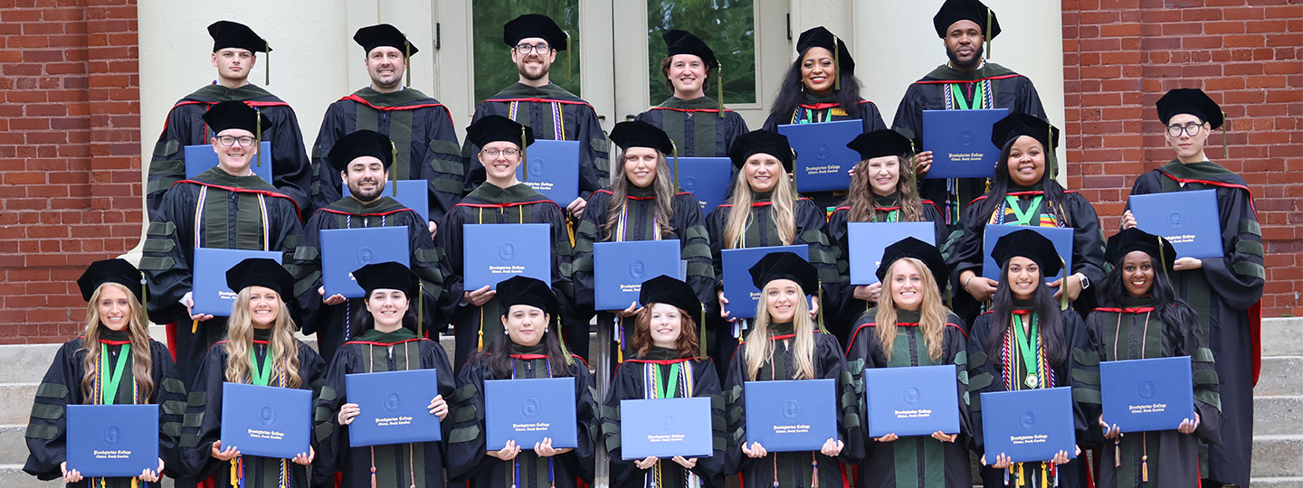 Class photo of the Class of 2024 Pharmacy Cohort in graduation regalia holding up their diplomas